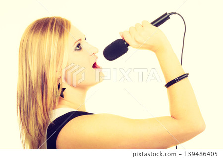 Pretty woman with microphone singing. Pretty woman with microphone singing. 139486405