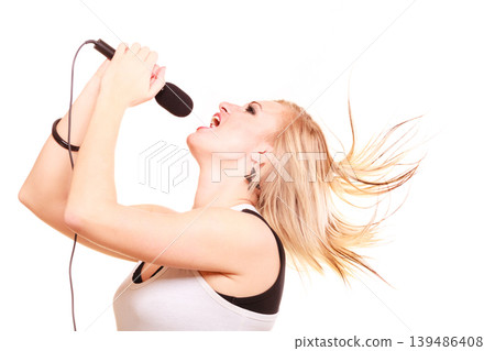 Blonde woman singing to microphone, profile view Blonde woman singing to microphone, profile view 139486408