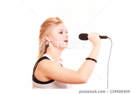 Blonde woman singing to microphone, profile view Blonde woman singing to microphone, profile view 139486409
