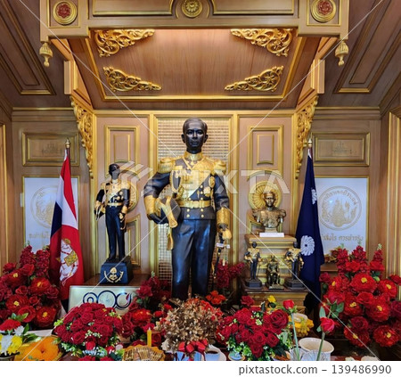 Statue of King Chulalongkorn Rama V in Ornate Shrine with Flowers and Thai Flags 139486990
