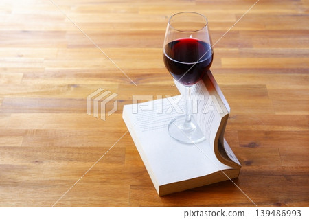A glass of wine and a book - Enjoying a book while drinking red wine A glass of wine and a book - Enjoying a book while drinking red wine 139486993