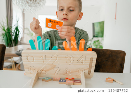 Child solving simple math problems using a wooden learning board. Educational activity supports early development and logical thinking. Child solving simple math problems using a wooden learning board. Educational activity supports early development and logical thinking. 139487732