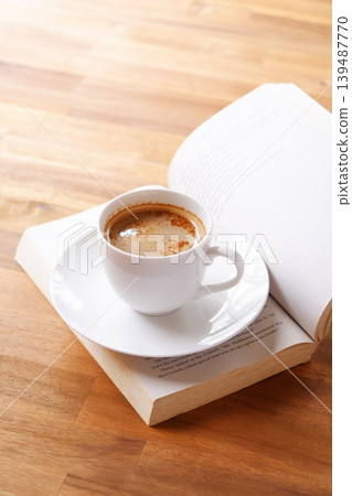 An image of enjoying reading while drinking coffee with an open book (Western book) and a coffee cup with coffee in it. An image of enjoying reading while drinking coffee with an open book (Western book) and a coffee cup with coffee in it. 139487770