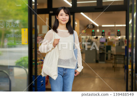一位年輕女子在超市購物,手裡拿著一個環保袋。 一位年輕女子在超市購物,手裡拿著一個環保袋。 139488549