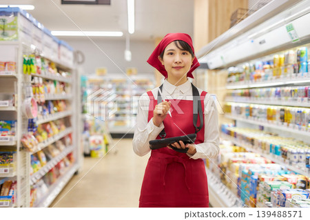 A young woman manages products using a tablet. A young woman manages products using a tablet. 139488571