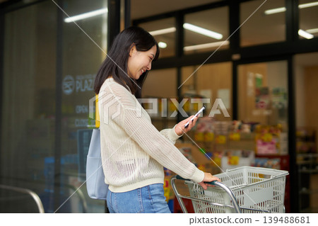 A young woman shopping with a shopping cart at a supermarket. A young woman shopping with a shopping cart at a supermarket. 139488681
