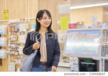 A young woman using her smartphone to pay at a self-checkout counter. 139488687
