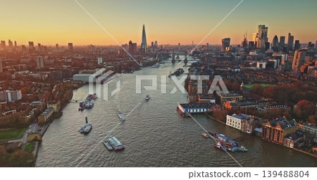 London cityscape panoramic aerial view, modern skyline at sunset, The Shard and Tower Bridge, boats navigate River Thames under bright colorful evening sky. England travel destination and landmarks London cityscape panoramic aerial view, modern skyline at sunset, The Shard and Tower Bridge, boats navigate River Thames under bright colorful evening sky. England travel destination and landmarks 139488804