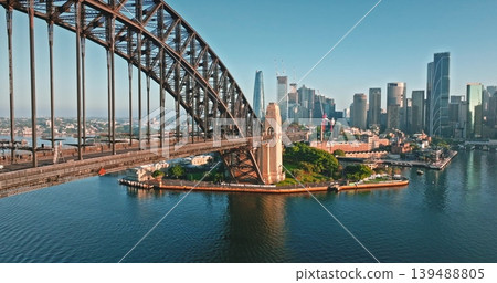 Sydney Harbour Bridge dominates the foreground, linking across the water to the vibrant cityscape featuring modern skyscrapers under a clear blue sky, capturing the dynamic urban environment Sydney Harbour Bridge dominates the foreground, linking across the water to the vibrant cityscape featuring modern skyscrapers under a clear blue sky, capturing the dynamic urban environment 139488805