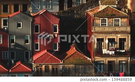 Porto houses vibrant facades and roofs, with laundry drying on lines, creating a lived-in urban scene under the afternoon sunlight. Aerial panorama shot of Portugal city. Architecture background Porto houses vibrant facades and roofs, with laundry drying on lines, creating a lived-in urban scene under the afternoon sunlight. Aerial panorama shot of Portugal city. Architecture background 139488859