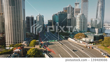 Australia, Sydney: cars driving highway road through Sydney's financial district, framed by towering skyscrapers buildings on a sunny morning. Modern city urban architecture. Aerial drone Australia, Sydney: cars driving highway road through Sydney's financial district, framed by towering skyscrapers buildings on a sunny morning. Modern city urban architecture. Aerial drone 139489086