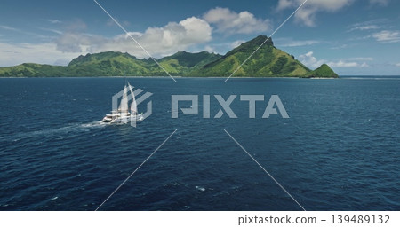 Fiji, Kuata island: Luxury catamaran sailing deep ocean water near green mountains tropical island, breathtaking aerial view. Remote wild nature paradise, exotic travel. Drone flight panorama Fiji, Kuata island: Luxury catamaran sailing deep ocean water near green mountains tropical island, breathtaking aerial view. Remote wild nature paradise, exotic travel. Drone flight panorama 139489132