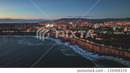 Portugal, Lisbon: Capturing the stunning cityscape of Cascais, Portugal, at twilight, with Atlantic Ocean waves crashing against the cliffs. Drone Portugal, Lisbon: Capturing the stunning cityscape of Cascais, Portugal, at twilight, with Atlantic Ocean waves crashing against the cliffs. Drone 139489159