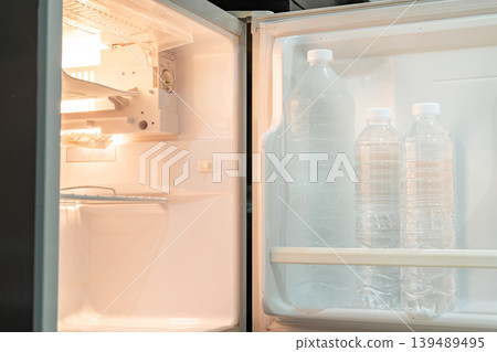 A small refrigerator sits beneath a wooden desk with chair, creating a clean hotel room setup that supports minibar service and compact guest comfort. A small refrigerator sits beneath a wooden desk with chair, creating a clean hotel room setup that supports minibar service and compact guest comfort. 139489495