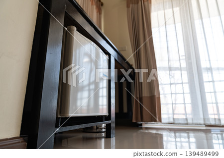 A small refrigerator sits beneath a wooden desk with chair, creating a clean hotel room setup that supports minibar service and compact guest comfort. 139489499