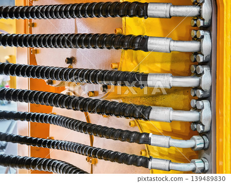Detail of machinery showing hydraulic hoses and connectors on a construction site during daylight hours Detail of machinery showing hydraulic hoses and connectors on a construction site during daylight hours 139489830