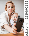 Authentic shot of neo mother and her newborn baby making a video call to father or relatives with laptop on a sofa in a living room. 139490131