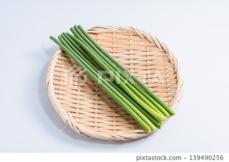 Garlic sprouts, fresh vegetables on a sieve, white background. Garlic sprouts, fresh vegetables on a sieve, white background. 139490256