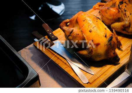 roasted chicken in a party dinner with a knife on a wooden board roasted chicken in a party dinner with a knife on a wooden board 139490516