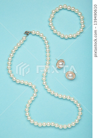 Beautiful pearl bracelet, earring, and necklace on blue background. Vertical photo Beautiful pearl bracelet, earring, and necklace on blue background. Vertical photo 139490610