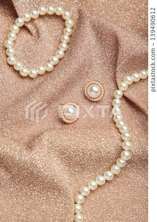 Beautiful pearl bracelet, earring, and necklace on beige texture background. Vertical photo Beautiful pearl bracelet, earring, and necklace on beige texture background. Vertical photo 139490612