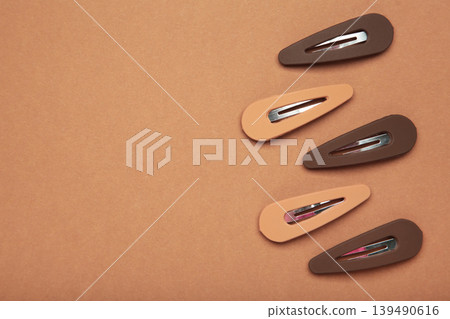 Beige and brown hair clips on brown background. Space for text Beige and brown hair clips on brown background. Space for text 139490616