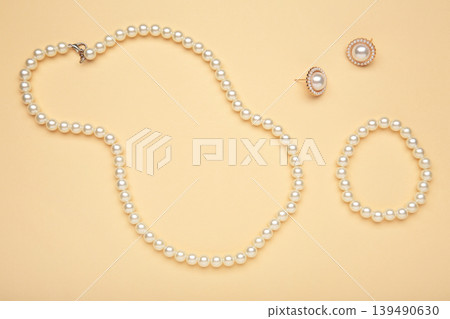 Beautiful pearl bracelet, earring, and necklace on beige background Beautiful pearl bracelet, earring, and necklace on beige background 139490630