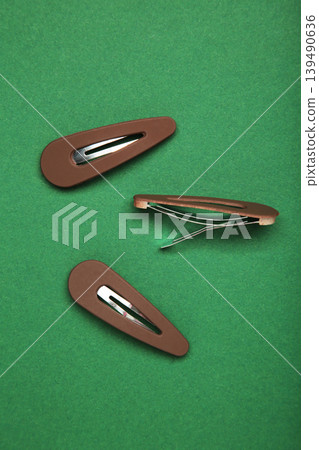 Brown hair clips on green background. Vertical photo Brown hair clips on green background. Vertical photo 139490636