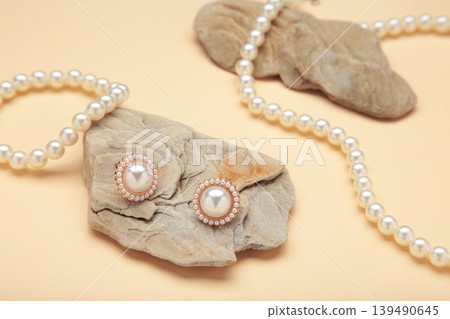 Beautiful pearl earring and necklace on stone on beige background Beautiful pearl earring and necklace on stone on beige background 139490645