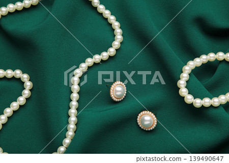 Beautiful pearl bracelet, earring, and necklace on green texture background Beautiful pearl bracelet, earring, and necklace on green texture background 139490647