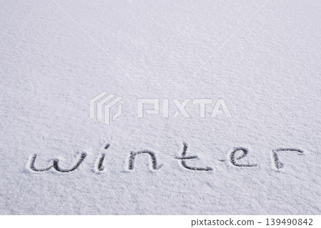 Written WINTER on snow background message ice outdoor on ground in winter. Writing text sign and drawing on field in frozen background. Weather is changing cold season has arrived. Mockup Copy space 139490842
