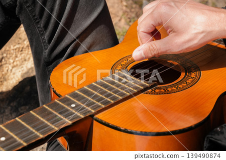 Close up hands of artist plays wooden acoustic guitar in autumnal park. Young songwriter plays string musical instrument hobby outside in nature fall time. Audio music healing Close up hands of artist plays wooden acoustic guitar in autumnal park. Young songwriter plays string musical instrument hobby outside in nature fall time. Audio music healing 139490874