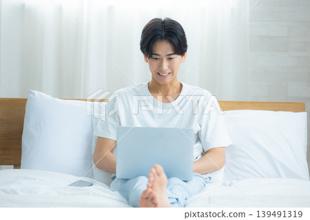 A man who plays a computer at bed A man who plays a computer at bed 139491319
