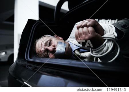 Man in trunk of car, kidnap and danger with violence, fear and rope in basement garage with shock. Crime, human trafficking and scared person tied in dark parking lot with risk, terror and robbery. Man in trunk of car, kidnap and danger with violence, fear and rope in basement garage with shock. Crime, human trafficking and scared person tied in dark parking lot with risk, terror and robbery. 139491843