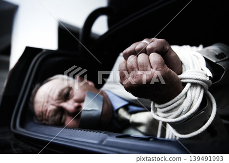 Car boot, kidnap and portrait of sad business man with tape, rope or crime danger in parking lot. Fear, stress and face of male victim in vehicle trunk with anxiety, horror or panic, scared or ransom Car boot, kidnap and portrait of sad business man with tape, rope or crime danger in parking lot. Fear, stress and face of male victim in vehicle trunk with anxiety, horror or panic, scared or ransom 139491993
