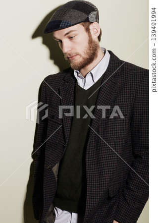 Fashion, thinking and young man in a studio with classy, elegant and fancy retro outfit and hat. Serious, handsome and male person from Australia with vintage style and accessory by gray background. Fashion, thinking and young man in a studio with classy, elegant and fancy retro outfit and hat. Serious, handsome and male person from Australia with vintage style and accessory by gray background. 139491994