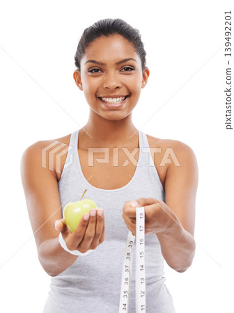 Woman, portrait and lose weight with a measuring tape and apple in white background or studio. Happy, model and healthy food for results in fitness, wellness and diet with nutrition and fruit Woman, portrait and lose weight with a measuring tape and apple in white background or studio. Happy, model and healthy food for results in fitness, wellness and diet with nutrition and fruit 139492201