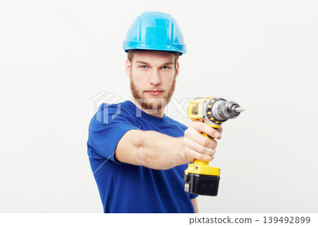 Construction worker man, power drill and studio portrait with hand for maintenance by white background. Person, employee or small business owner with tools, helmet and job at repair services company Construction worker man, power drill and studio portrait with hand for maintenance by white background. Person, employee or small business owner with tools, helmet and job at repair services company 139492899