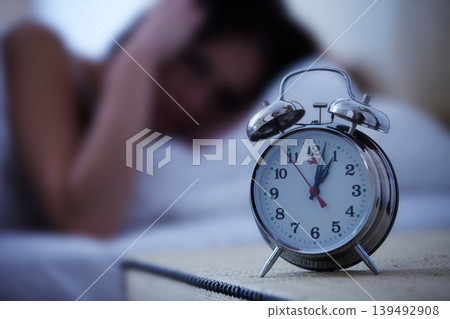 Alarm, clock and frustrated woman in a bed with hands on ears for noise, sound or alert at home. Time, bell and female person in a bedroom blur with fatigue, burnout or sleeping late from insomnia 139492908