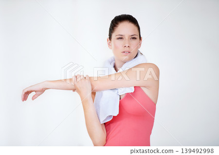 Stretching arm, thinking or woman in gym with towel for fitness, flexibility or wellness on white background. Serious, athlete or healthy sports person ready for workout, training or exercise warm up Stretching arm, thinking or woman in gym with towel for fitness, flexibility or wellness on white background. Serious, athlete or healthy sports person ready for workout, training or exercise warm up 139492998