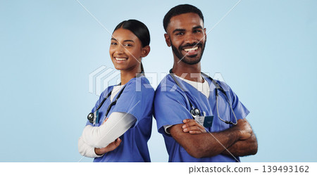 Portrait, healthcare and arms crossed with a medicine team in studio on a blue background for trust. Medical, smile or wellness with a young man and woman nurse looking confident for treatment Portrait, healthcare and arms crossed with a medicine team in studio on a blue background for trust. Medical, smile or wellness with a young man and woman nurse looking confident for treatment 139493162