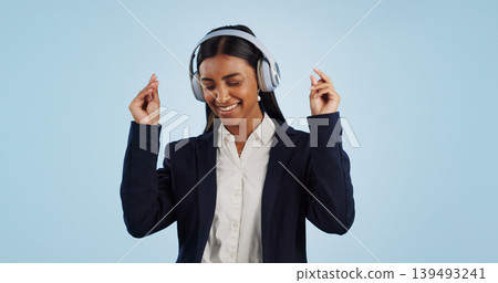 Headphones, dancing or happy businesswoman in studio for music isolated on blue background. Energy, smile or calm female person streaming a radio song, sound or audio on online subscription to relax Headphones, dancing or happy businesswoman in studio for music isolated on blue background. Energy, smile or calm female person streaming a radio song, sound or audio on online subscription to relax 139493241