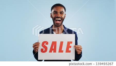 Excited man, portrait and sale sign for advertising, deal or discount against a blue studio background. Happy male person showing billboard or poster for marketing, promotion or special on mockup Excited man, portrait and sale sign for advertising, deal or discount against a blue studio background. Happy male person showing billboard or poster for marketing, promotion or special on mockup 139493267