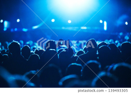 People, blue and crowd for concert, performance or stage in arena for rock, psychedelic or electric music. Lens flare, light and equipment with person, holding and smartphone for social media post People, blue and crowd for concert, performance or stage in arena for rock, psychedelic or electric music. Lens flare, light and equipment with person, holding and smartphone for social media post 139493305