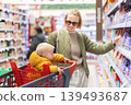 Caucasian mother shopping with her infant baby boy child choosing products in department of supermarket grocery store 139493687