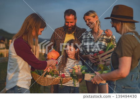 Farmers carrying basket with harvest and looking at homegrown vegetables outdoors at community garden. 139494430