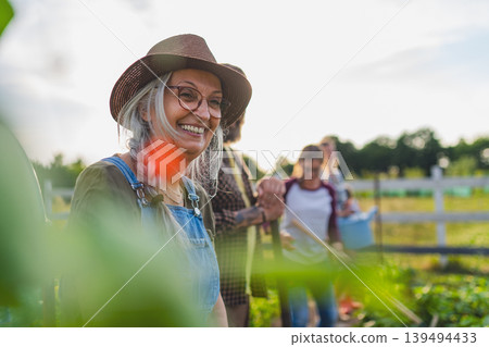 Happy farmers or gardeners working outdoors at community farm. 139494433