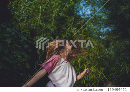 Carefree girl spinning in garden during warm summer day. Carefree girl spinning in garden during warm summer day. 139494451