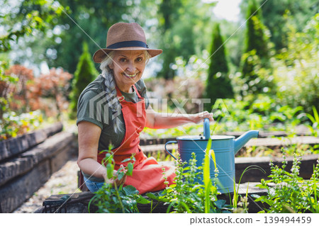 Woman watering plants in organic garden on sunny summer day. 139494459