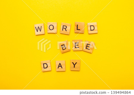 Top view of World bee day text on yellow background Top view of World bee day text on yellow background 139494864